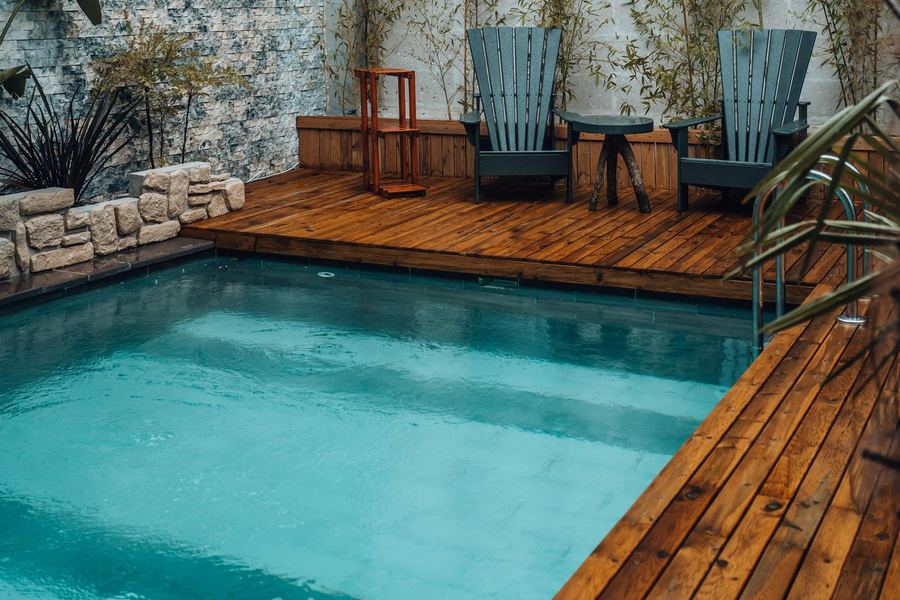 Compact garden pool with wooden deck, bamboo planting and outdoor seating integrated around the water